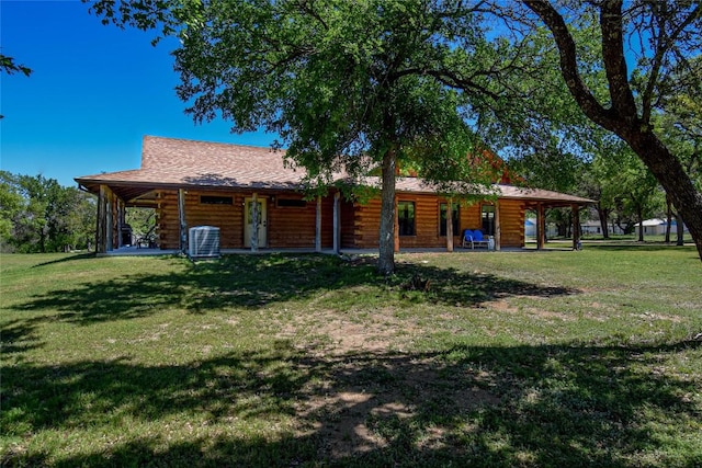 rear view of house with a lawn, central AC unit, and log siding