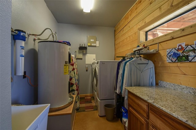 laundry area with washing machine and clothes dryer, light colored carpet, water heater, wood walls, and cabinet space