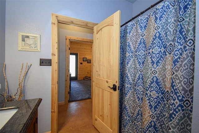 full bathroom with baseboards, curtained shower, vanity, and finished concrete floors