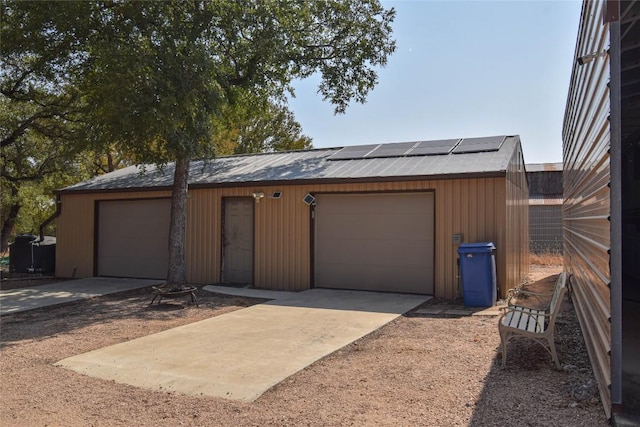 detached garage with roof mounted solar panels and driveway