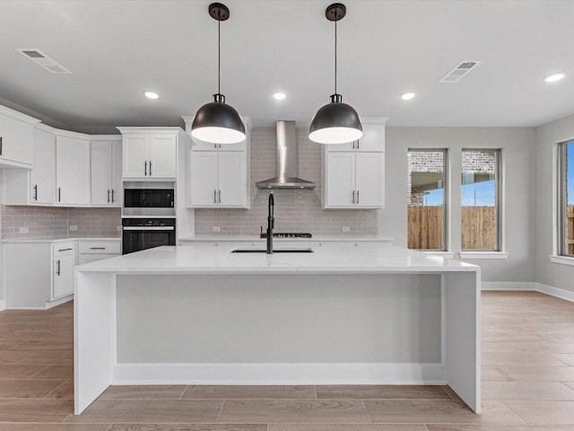 7413 Desert Needle Dr, Lago Vista, TX 78645 - kitchen with wall chimney exhaust hood, backsplash, a large island, white cabinetry, and wood tiled floors