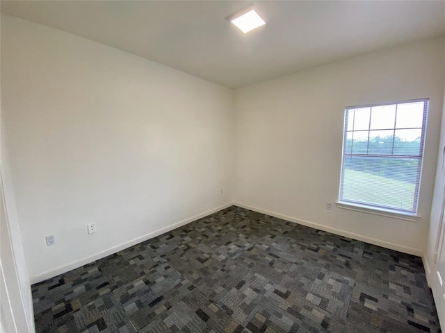 empty room featuring dark carpet and baseboards