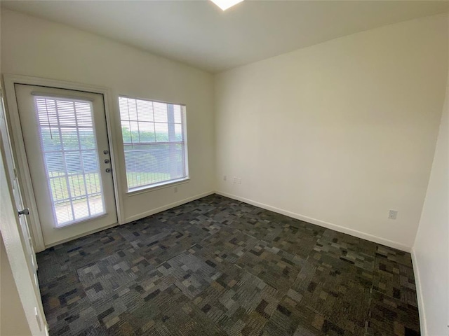 unfurnished room with dark carpet and baseboards