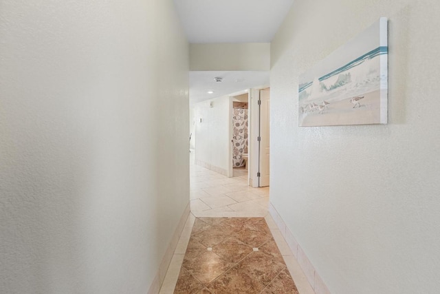 hallway with recessed lighting, baseboards, and light tile patterned floors