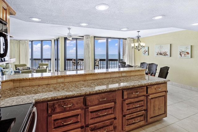 kitchen featuring a water view, a textured ceiling, baseboards, and light tile patterned floors