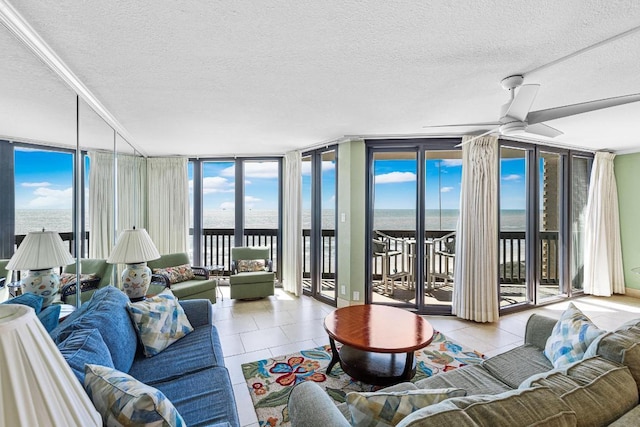 living room featuring a textured ceiling, tile patterned floors, a water view, and a wall of windows
