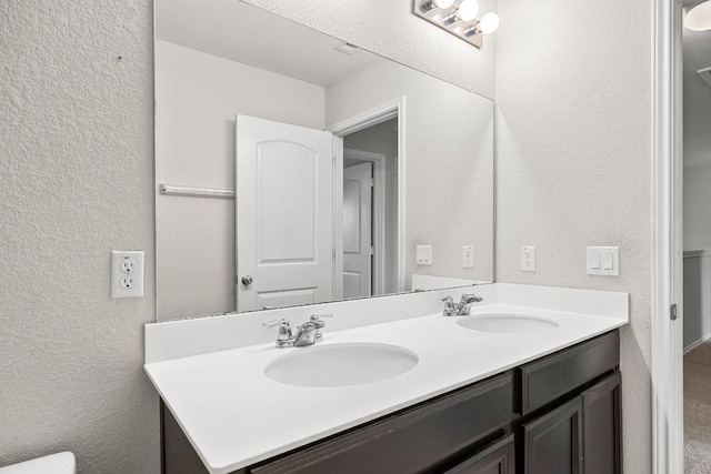 7001 Midlothian Dr, Austin, TX 78754 - bathroom with double vanity, a textured wall, and toilet