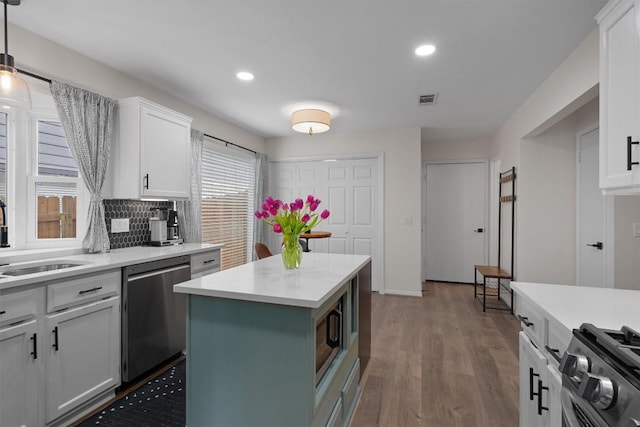 2003 Ploverville Ln, Austin, TX 78728 - kitchen featuring stainless steel appliances, light countertops, recessed lighting, wood finished floors, and white cabinetry