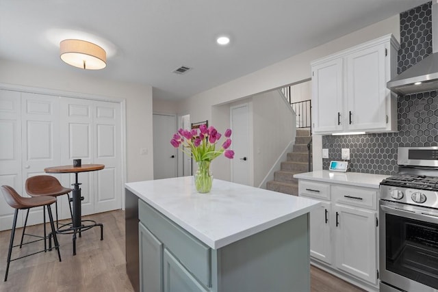 2003 Ploverville Ln, Austin, TX 78728 - kitchen with wall chimney exhaust hood, stainless steel range with gas cooktop, tasteful backsplash, light countertops, and a kitchen island