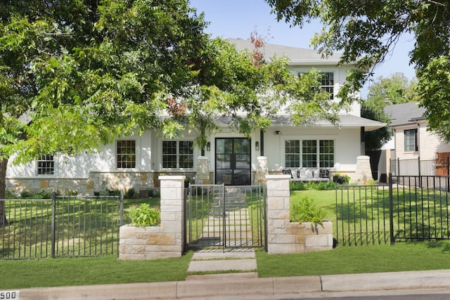 obstructed view of property featuring a gate, stone siding, stucco siding, a fenced front yard, and a front lawn