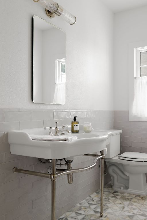 bathroom featuring toilet, tile walls, a healthy amount of sunlight, and wainscoting