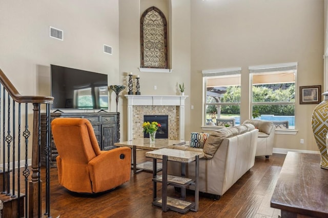 2505 Livenza Pl, Leander, TX 78641 - living room featuring a towering ceiling, dark wood finished floors, a tiled fireplace, and stairs