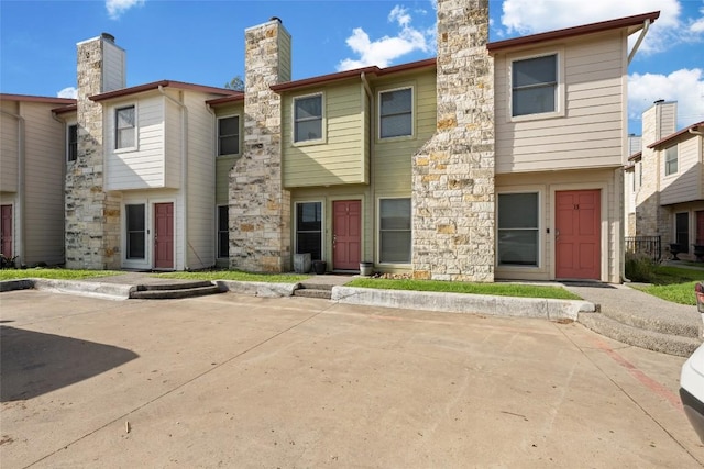 view of front facade with stone siding and a chimney