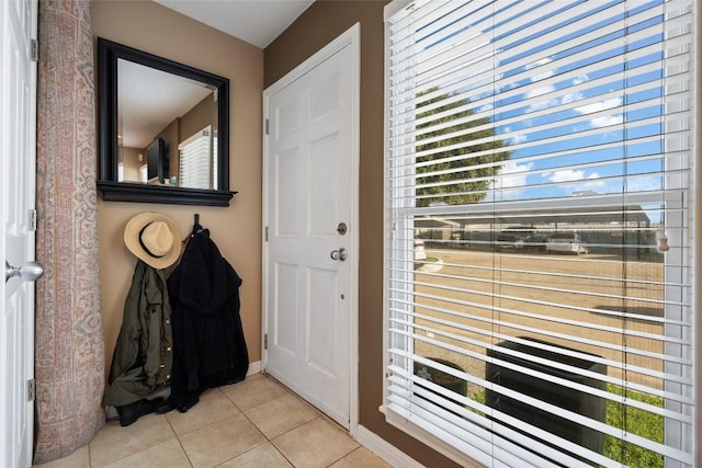 entryway with baseboards and light tile patterned floors