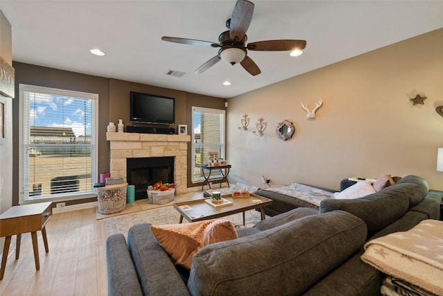 living area featuring plenty of natural light, visible vents, a fireplace, and ceiling fan