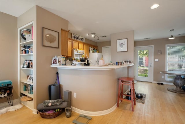 kitchen featuring light countertops, a breakfast bar, light wood-style flooring, a peninsula, and freestanding refrigerator