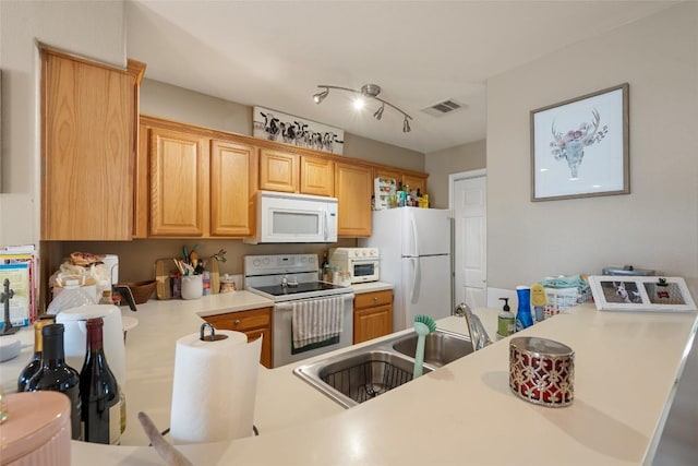 kitchen with visible vents, a sink, white appliances, and light countertops