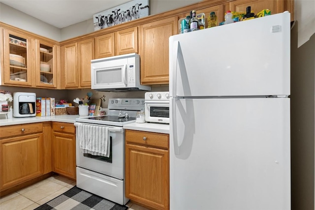 kitchen featuring glass insert cabinets, light countertops, white appliances, and light tile patterned floors