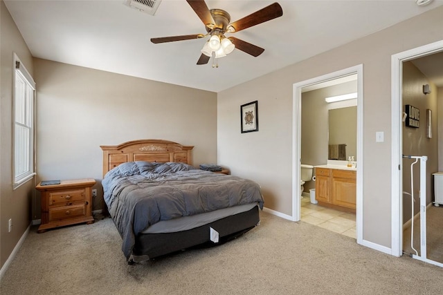 bedroom with visible vents, ensuite bath, baseboards, light colored carpet, and ceiling fan