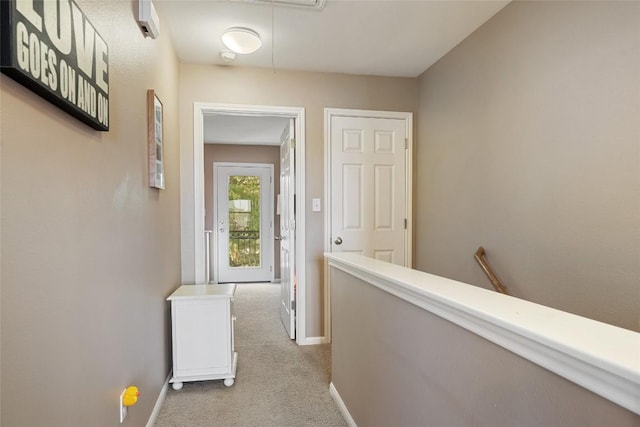 hallway with attic access, carpet floors, an upstairs landing, and baseboards