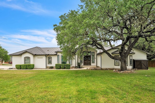 ranch-style home with stucco siding, a front lawn, a standing seam roof, and metal roof