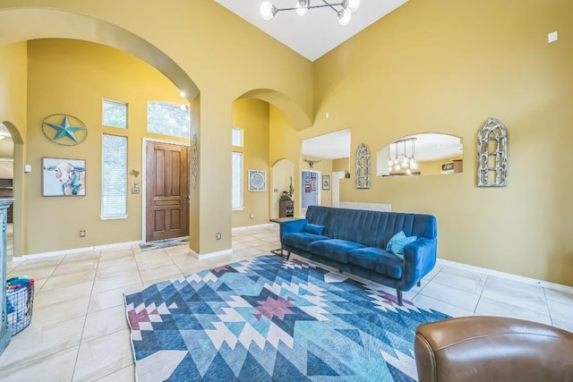 living room with arched walkways, a towering ceiling, an inviting chandelier, and light tile patterned flooring