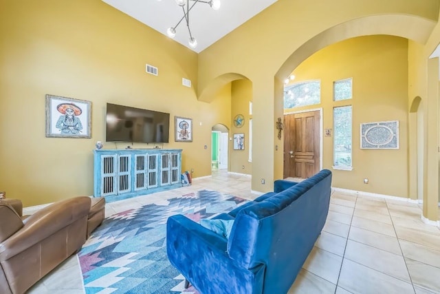 living room featuring baseboards, arched walkways, a towering ceiling, and light tile patterned floors
