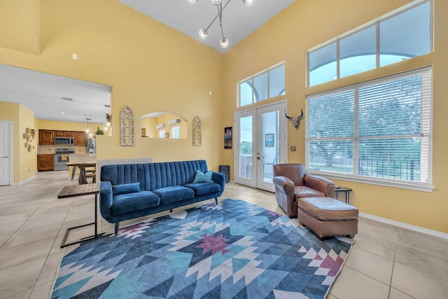 living room with baseboards, french doors, a towering ceiling, and light tile patterned floors