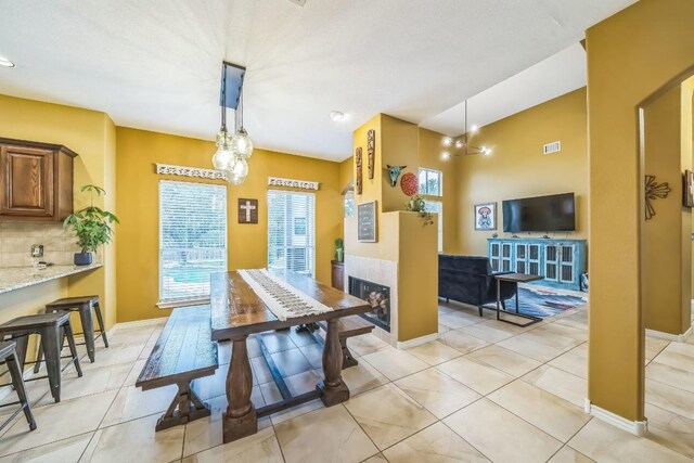 dining space with baseboards, a notable chandelier, visible vents, and light tile patterned floors
