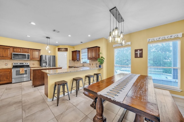 kitchen featuring stainless steel appliances, visible vents, plenty of natural light, and tasteful backsplash