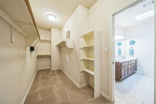 walk in closet featuring light carpet, visible vents, and a sink