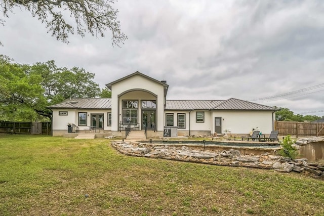 back of house with fence, a swimming pool, a yard, and metal roof