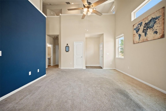 unfurnished bedroom with carpet floors, a high ceiling, baseboards, and multiple windows
