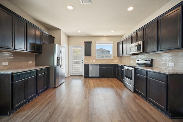 kitchen with decorative backsplash, recessed lighting, light wood-style floors, and appliances with stainless steel finishes