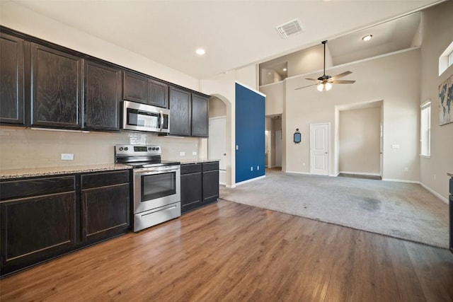 kitchen featuring ceiling fan, arched walkways, a high ceiling, appliances with stainless steel finishes, and visible vents
