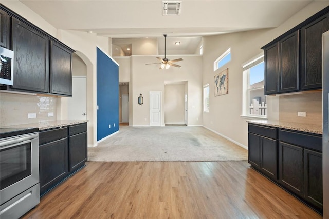 kitchen with stainless steel appliances, visible vents, arched walkways, baseboards, and ceiling fan