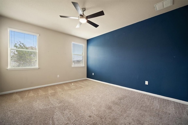unfurnished room with ceiling fan, carpet floors, visible vents, and baseboards
