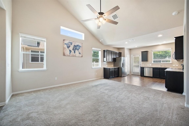 unfurnished living room with light carpet, baseboards, recessed lighting, ceiling fan, and high vaulted ceiling
