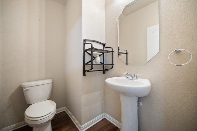 bathroom with wood finished floors, toilet, baseboards, and a sink