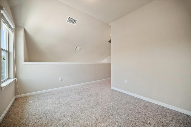 spare room with carpet floors, visible vents, and baseboards