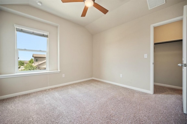 unfurnished bedroom with a spacious closet, carpet floors, baseboards, lofted ceiling, and visible vents