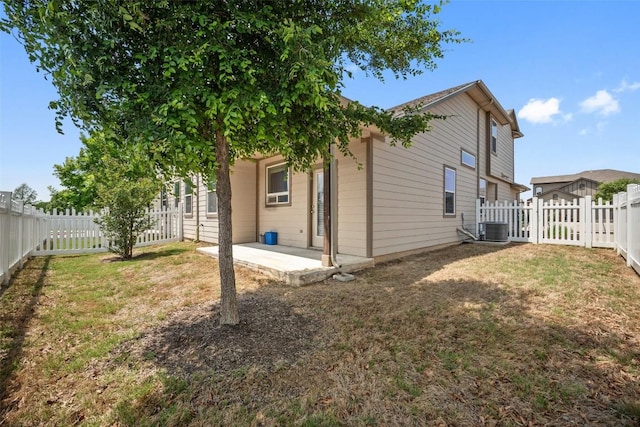 rear view of house featuring a patio area, a lawn, a fenced backyard, and central AC unit