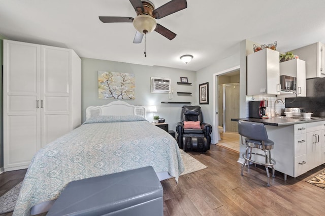 bedroom featuring wood finished floors and a wall unit AC