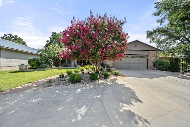 obstructed view of property featuring fence, concrete driveway, a front yard, and a garage