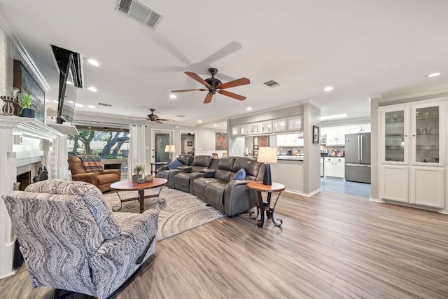 living area featuring a ceiling fan, light wood-style floors, a tile fireplace, visible vents, and recessed lighting