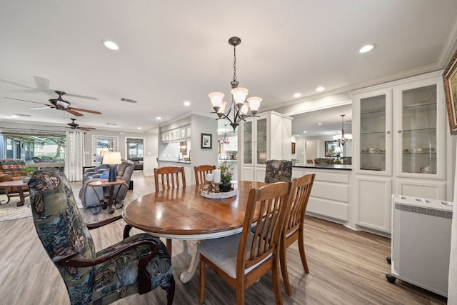 dining space featuring crown molding, ceiling fan with notable chandelier, light wood finished floors, visible vents, and recessed lighting