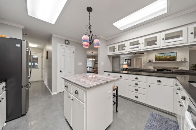 kitchen featuring white cabinets, a center island, freestanding refrigerator, and ornamental molding