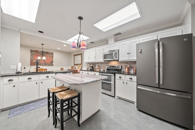 kitchen featuring a sink, white cabinetry, a chandelier, a skylight, and appliances with stainless steel finishes