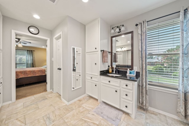 bathroom with a healthy amount of sunlight, vanity, baseboards, and ensuite bathroom