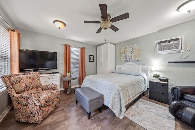 bedroom with dark wood finished floors, an AC wall unit, and multiple windows